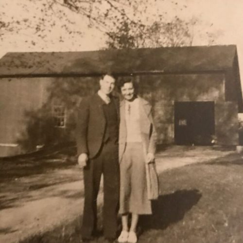 A man and woman standing in front of a barn.