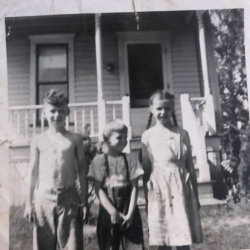 A group of children standing in front of a house.