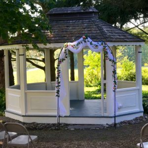 A white gazebo with flowers and a blue ribbon.