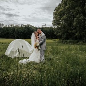 A bride and groom kissing in the grass.