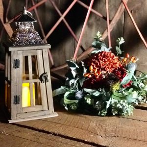 A wooden lantern sitting next to some flowers.